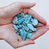 Someone holding handfull of larimar stones